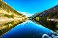 Reflections of blue sky, trees and mountains in the smooth surface on the crystal clear water of Crown Lake Royalty Free Stock Photo