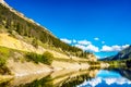 Reflections of blue sky, trees and mountains in the smooth surface on the crystal clear water of Crown Lake Royalty Free Stock Photo