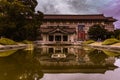 Symmetrical architecture under a blue sky and reflections in a pond with green tones