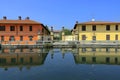 REFLECTIONS OF COLORFUL BUILDINGS ON THE WATER OF THE RIVER NAVIGLIO IN GAGGIANO VILLAGE IN ITALY