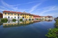 REFLECTIONS OF COLORFUL BUILDINGS ON THE WATER OF THE RIVER NAVIGLIO IN GAGGIANO VILLAGE IN ITALY