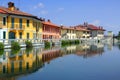 REFLECTIONS OF COLORFUL BUILDINGS ON THE WATER OF THE RIVER NAVIGLIO IN GAGGIANO VILLAGE IN ITALY
