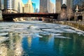 Reflections of colorful Chicago cityscape on a frozen chicago river with ice chunks floating under a bridge Royalty Free Stock Photo