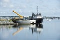 Reflections of crane and docked offshore supply vessel