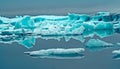 Reflections of crystal blue and white ice floes in black dark glassy smooth water in dim gloomy mystic light - Jokulsarlon Glacier