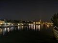 Eiffel tower view and reflections of lights on the river at bridge of Arts at night, Paris.