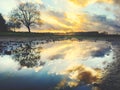 Reflections in a puddle of a Beautiful dramatic sunset over a field