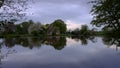 Reflections of St Leonard`s church in Hartley Mauditt Pond, South Downs National Park, UK