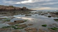 Reflections in tidal pools at low tide on a rugged coastline under a cloudy sky Royalty Free Stock Photo