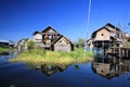 Reflections of traditional stilts wood houses in smooth as glass water contrasting with cloudless blue sky - Inle Lake, Myanmar Royalty Free Stock Photo