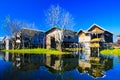 Reflections of traditional stilts wood houses in smooth as glass water contrasting with cloudless blue sky Royalty Free Stock Photo