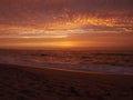 Reflections on water at sunset on the beach as waves break on the sand Royalty Free Stock Photo