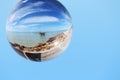 Reflective ball with sky, pier and rocks
