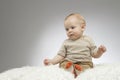 Reflective cute boy sitting on the white blanket, studio shot, isolated on grey background, funny baby portrait Royalty Free Stock Photo