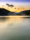 Golden, reflective lake vertical shot during sunset with dramatic sky Royalty Free Stock Photo