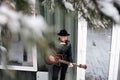 Reflective musician in a leather jacket playing guitar next to a house door