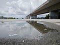 reflective pool of water on the asphalt street beneath the bridge crossing.