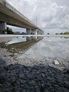 reflective pool of water on the asphalt street beneath the bridge crossing.