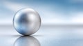 Reflective silver sphere on smooth surface with soft blue background Royalty Free Stock Photo