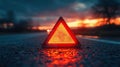 Warning triangle reflects the sunset glow on a wet road, signaling potential danger ahead. Royalty Free Stock Photo
