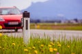 Road in the summer: reflector post, cars, flowers and green grass