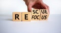 Refocus and rescue symbol. Businessman turns cubes and changes the word `refocus` to `rescue`. Beautiful white table, white