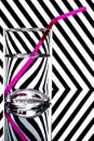 Refraction of light by a glass on a black and white striped background with drinking straw. Abstract glass art Royalty Free Stock Photo