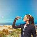 Refreshed and ready to flex. a sporty young woman drinking water outdoors.