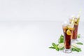 Refreshing alcohol beverage cuba libre with cola, ice, mint, lime, straw in two wet long glasses in modern white kitchen interior. Royalty Free Stock Photo