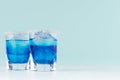 Refreshing alcohol drinks blue Hawaii in two misted elegant shot glass with ice cubes and salt rim in modern pastel mint beach bar Royalty Free Stock Photo