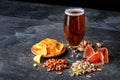 Refreshing alcoholic beverage. Dark ale in a glass. Composition of snacks. Beer and appetizers on a table background