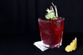 Refreshing alcoholic drink with berries, ice vodka and gin, lemon peel served in glass cup on the counter on black background Royalty Free Stock Photo