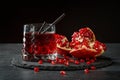 Refreshing alcoholic drinks. A composition of a pomegranate beverage and a cut garnet on a black background. Fruity red