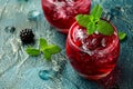 Refreshing Blackberry cocktail with ice and mint on rustic background