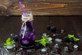 Refreshing blackberry juice in vintage eco style bottle on rustic dark wooden table. Cold summer berry drink with ice and mint. Co