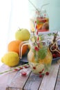 Refreshing cocktail, detox water from organic fruits and berries, mint leaves in glass jugs on a wooden table