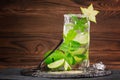 Refreshing cocktail with rum, lime, mint, crushed ice and carambola on a wooden background. A glass of alcohol mojito. Copy space. Royalty Free Stock Photo