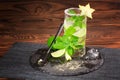 Refreshing cocktail with rum, lime, mint, crushed ice and carambola on a wooden background. A glass full of mojito. Copy space. Royalty Free Stock Photo