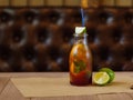 A refreshing cocktail with slices of lemon, green lime and leaves of mint on a blurred wooden background.