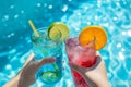 refreshing cocktails in the pool. Colorful iced cocktails garnished with lime and orange slices. bright sunny day. Rest and