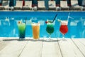 Refreshing cocktails on wooden deck near swimming pool