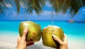 Refreshing coconut cocktail in woman and man hand. Coconut water drink on the Maldives beach. Royalty Free Stock Photo