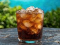 Refreshing cola drink with ice in a glass on a patio table