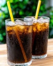 Refreshing cola drinks with ice and straws on a wooden table.