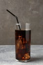 Refreshing cola with ice cubes and drinking straw in glass on light textured table against grey background, closeup Royalty Free Stock Photo