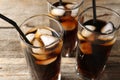 Refreshing cola with ice cubes and drinking straws in glasses on wooden table, closeup Royalty Free Stock Photo