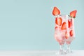 Refreshing cold strawberry beverage with red fruit slices, ice cubes, sparkling water in two misted glasses in modern mint color. Royalty Free Stock Photo