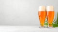 Refreshing craft beer in glasses with foam and palm leaves