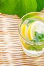 Refreshing detox infused sassy water with lemon fresh mint ginger in glass on wicker table with houseplants in background. Healthy Royalty Free Stock Photo