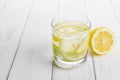 Refreshing drink for health, lemon water in a glass and yellow linden flowers on a white table